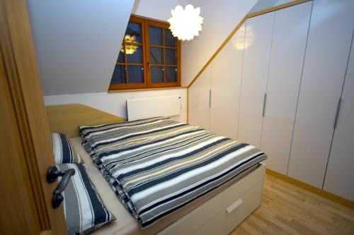 a bedroom with a bed with a striped blanket on it at Apartmaji Lajf in Kranjska Gora