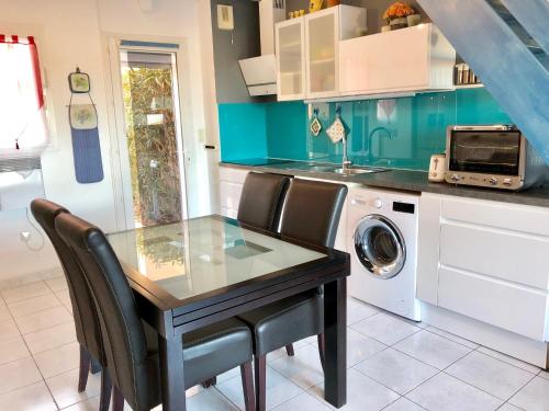 a kitchen with a table and chairs and a washing machine at Barcaresa-Villa Vue Mer Accès Direct Plage - Piscine in Le Barcarès
