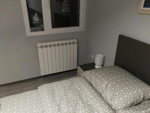 a bedroom with a bed and a radiator and a window at Apartmani Janjic in Banja Luka