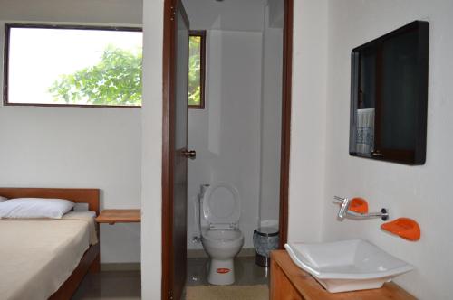 a bathroom with a toilet and a sink and a tv at La Facha Hostal Restaurant Surf in Mompiche
