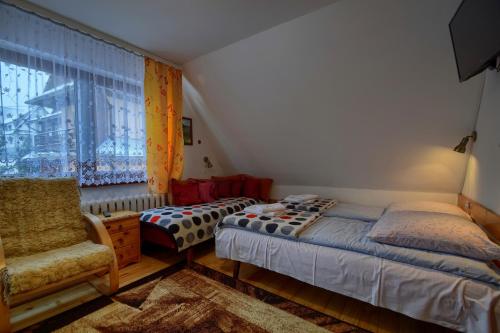 1 dormitorio con 2 camas, silla y ventana en Agro u Marka en Bukowina Tatrzańska