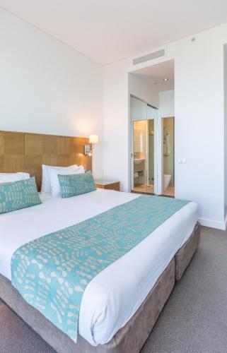 a bedroom with a large bed with blue and green sheets at Wyndham Resort Surfers Paradise in Gold Coast