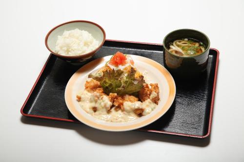 a plate of food on a black tray with rice at Hotel Rumieru Hyuga in Hyuga
