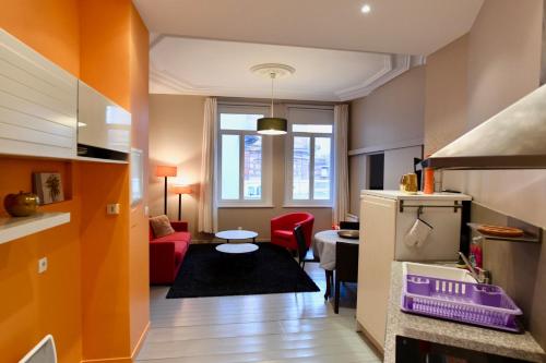 Appartement Week-end في دونكيرك: مطبخ وغرفة معيشة مع أريكة حمراء