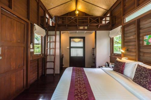 a bedroom with a bed and a loft bed with a ladder at Cocohut Beach Resort Koh Phangan in Haad Rin