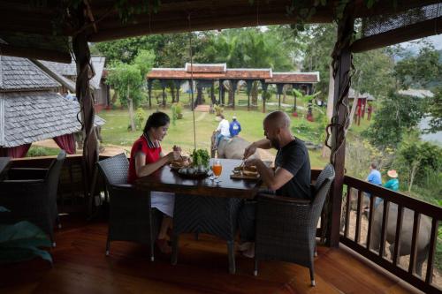 a man and a woman sitting at a table on a porch at Shangri-Lao Resort in Luang Prabang