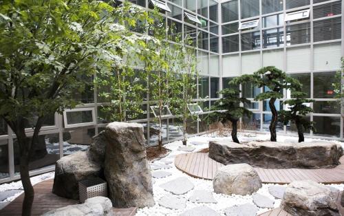 a building with a garden with trees and rocks at Benikea The Bliss Hotel in Incheon