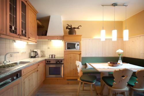 kuchnia z drewnianymi szafkami i stołem z krzesłami w obiekcie LEO Appartements w Mayrhofen