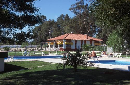 une maison à côté d'une piscine avec une maison dans l'établissement Parque de Campismo Orbitur Evora, à Évora