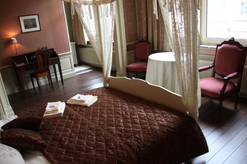 a bedroom with a bed and a table and chairs at La Porte Cochère in Ypres