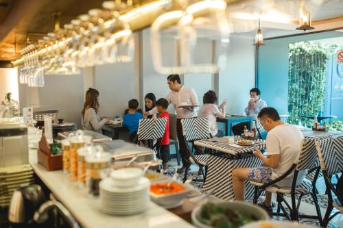 a group of people sitting at tables in a restaurant at De Chai Oriental Nimman - SHA Plus in Chiang Mai