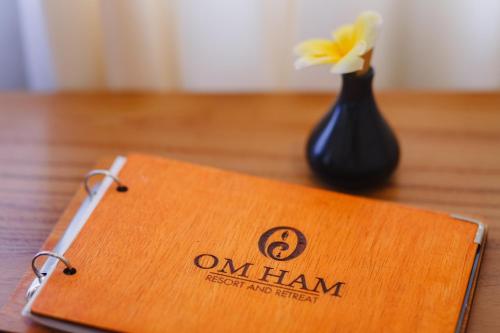 a wooden sign on a table with a vase at Om Ham Retreat and Resort in Ubud