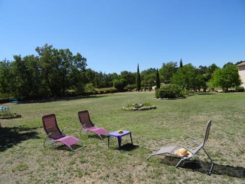 trois chaises et une table dans un champ dans l'établissement Cante Grillet - 295 Chemin des Contards - 84480 Lacoste, à Lacoste