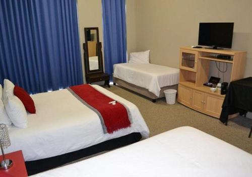 
a hotel room with two beds and a television at Dante Deo Guesthouse in Bloemfontein
