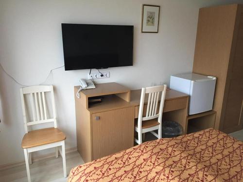 a bedroom with a desk with a television and two chairs at Carolina Hotel in Pärnu