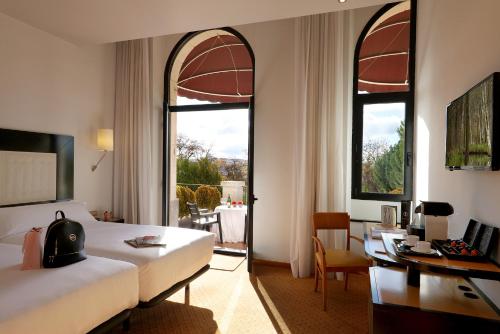 Habitación de hotel con cama, escritorio y ventanas en Abba Burgos, en Burgos