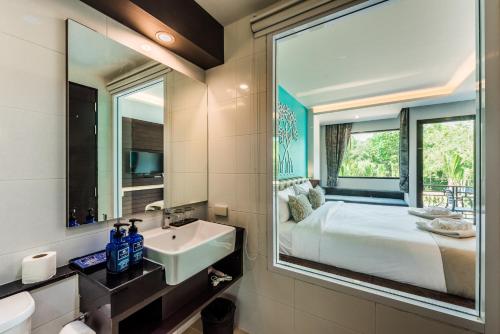 a bathroom with a sink and a bed with a mirror at River Front Krabi Hotel in Krabi town