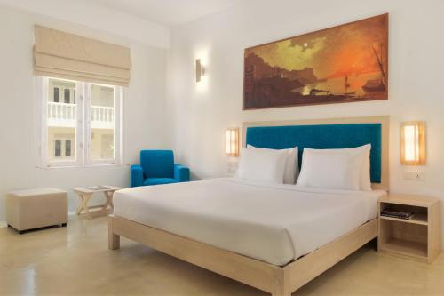 a bedroom with a large white bed and a blue chair at Epic Unawatuna in Unawatuna