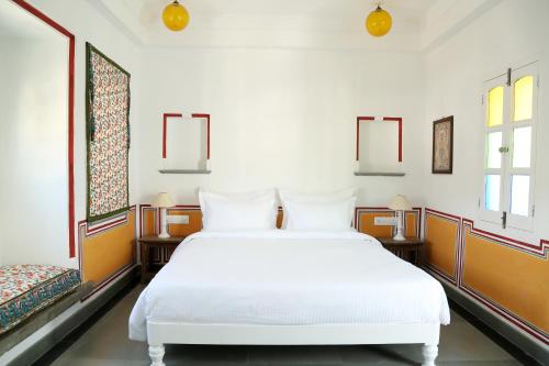 a bedroom with a white bed and two windows at Little Garden Guest House in Udaipur
