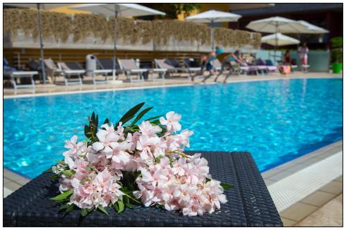 a bouquet of pink flowers sitting on a table near a swimming pool at Catania Hills Residence in San Gregorio di Catania