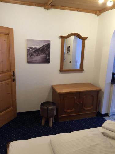 a bedroom with a dresser and a mirror and a bed at Brenners Dorfstube in Fieberbrunn