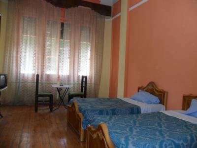 a bedroom with two beds and a table and a television at Berlin Hotel in Cairo
