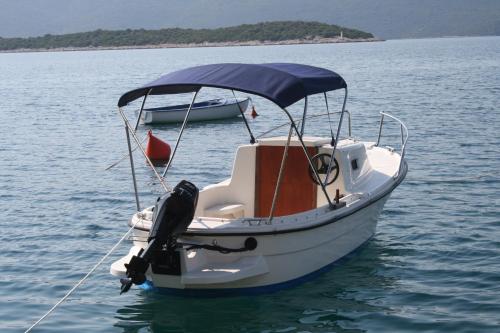 a small white boat in the water on a lake at Apartments Tamaris in Klek