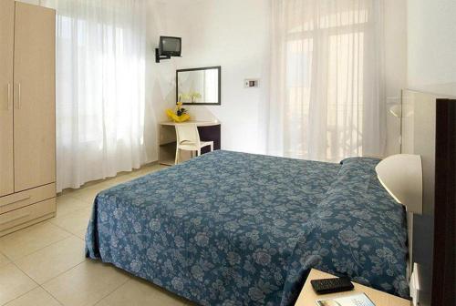 - une chambre avec un lit doté d'un couvre-lit bleu et d'un bureau dans l'établissement Hotel Nettuno, à Misano Adriatico