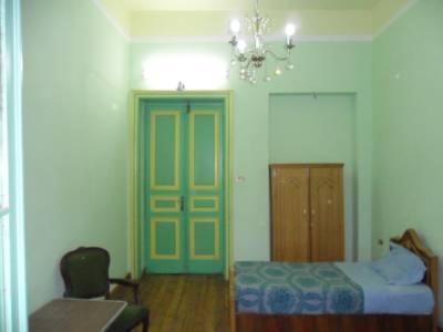 a room with a bed and a chair and a door at Berlin Hotel in Cairo