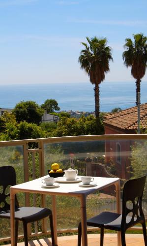 a white table and chairs on a balcony with palm trees at Catania Hills Residence in San Gregorio di Catania