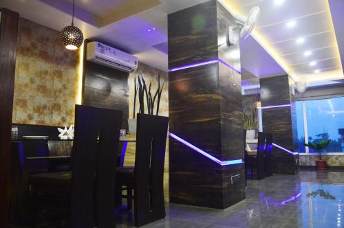 a restaurant with a bar with purple lights on the wall at Hotel Royal Palace in Bishnāth