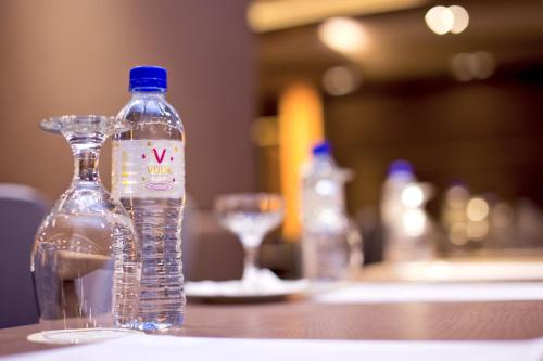 a bottle of water sitting on a table with a glass at Vouk Hotel Suites, Penang in George Town