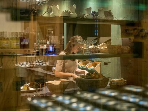 a woman standing behind a counter with a basket of food at Farmhotel Moosmair in Campo Tures