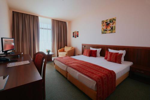 a hotel room with a bed, desk, and television at Kristal Hotel - All inclusive in Golden Sands