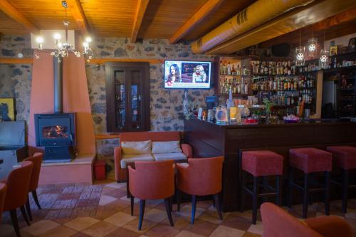 a bar with red chairs and a television in a room at To Spitiko in Palaios Agios Athanasios