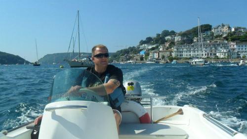 a man sitting on a boat in the water at Teign Head Apartment in Newton Abbot