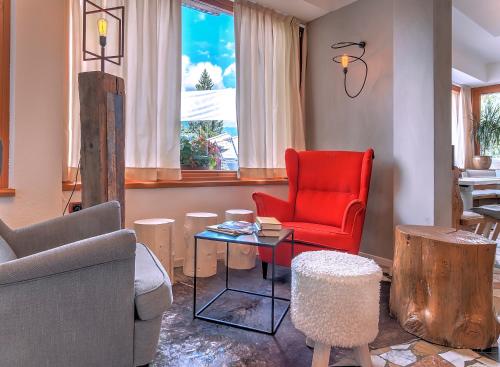 a living room with a red chair and a table at Hotel Folgarida in Folgarida