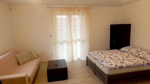 1 dormitorio con cama, sofá y ventana en Apartmány Andrea, en Břeclav