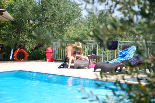 a man and a woman sitting next to a swimming pool at Anatoli Labreon in Agia Marina