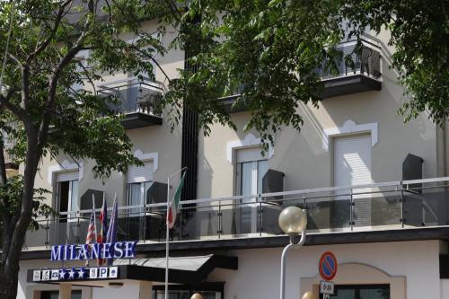 un bâtiment avec drapeaux devant lui dans l'établissement Hotel Milanese, à Rimini