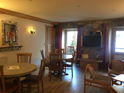 a dining room with tables and chairs and a television at Hotel Le Centre in Brides-les-Bains