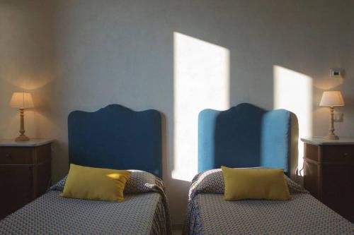 2 Betten in einem Zimmer mit 2 blauen Stühlen in der Unterkunft Masseria Rosario in Grottaglie