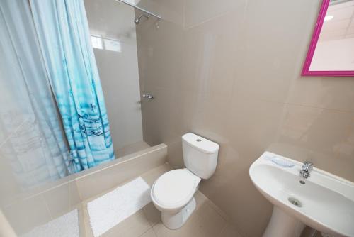 biała łazienka z toaletą i umywalką w obiekcie Punta Huanchaco Hostel w mieście Huanchaco