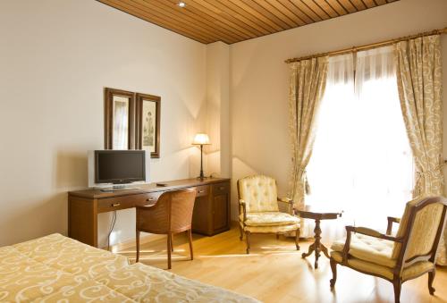 a bedroom with a desk with a television and a bed at Bodegas Hacienda Albae in Argamasilla de Alba