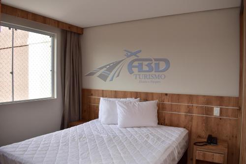 1 dormitorio con 1 cama y un cartel en la pared en Casa da Madeira Caldas Novas, en Caldas Novas