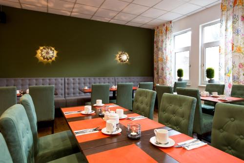 a dining room with tables and green chairs at ACHAT Hotel Hockenheim in Hockenheim