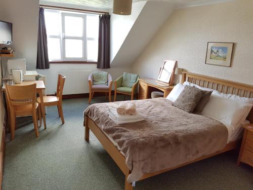 a bedroom with a bed and a table and chairs at Malin House Hotel in Saundersfoot