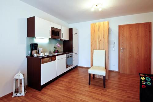 a kitchen with white cabinets and a chair in a room at Haus Bergsonne in Flachau
