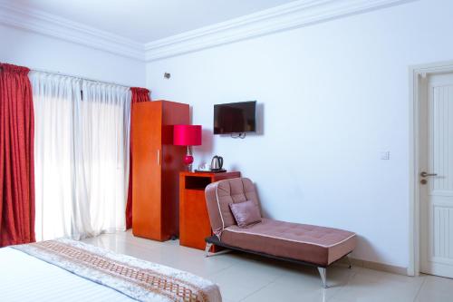 a bedroom with a chair and a television in it at Le Feto 3 in Dakar