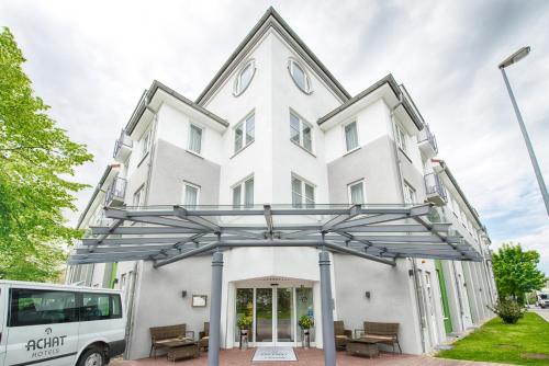 un bus garé devant un bâtiment blanc dans l'établissement ACHAT Hotel Leipzig Messe, à Leipzig